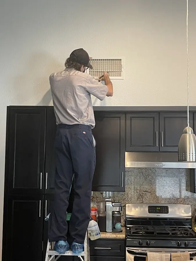 Technician inspecting an air vent during HVAC service in Framingham